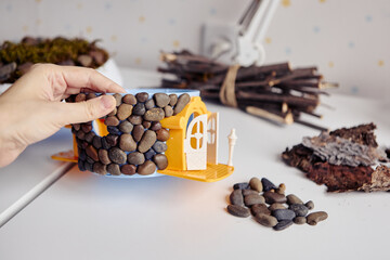 Hand gluing small pebbles to create a DIY stone house craft.
Creative handmade project shows detailed process and design.
Natural materials inspire eco craft ideas for kids and home.
