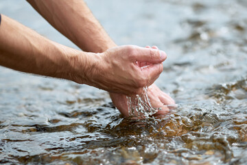 Hands scoop clear river water in a peaceful natural scene.
Flowing stream reflects sunlight and purity of nature.
Fresh outdoor moment symbolizes cleanliness and mindfulness.
