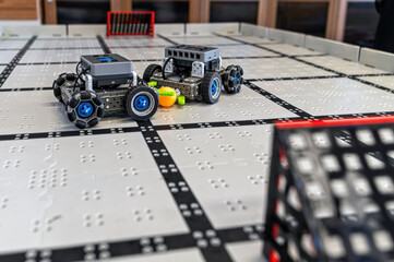Small robots compete in a technology display at a robotics event in a classroom setting