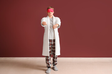 Male sleepwalker in pajamas near burgundy wall