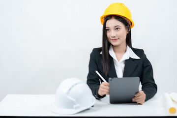 An Asian female engineer in a studio shot with a white background is seated at her desk, reviewing a greenprint on a tablet, symbolizing how industry leaders now engage audiences via social media.