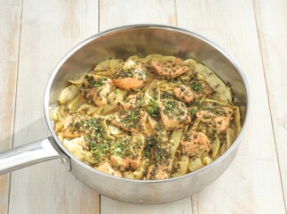 A dish of salmon and artichoke is presented in a pan. The Salmon pieces have been seasoned with herbs. It looks like a lovely weeknight meal, ready to serve