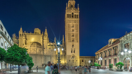 Fototapeta premium La Giralda and Seville Cathedral day to night timelapse glowing under the night sky.