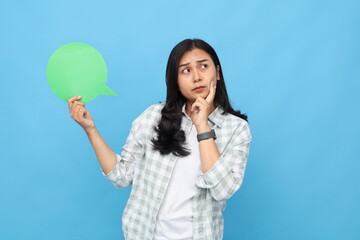 Young Asian woman showing a blank green paper page, with a saying that says something, an expression of imagining, thinking or dreaming about something, looking at the paper.