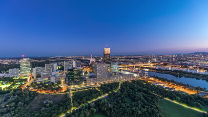 Aerial panoramic view over Vienna city with skyscrapers, historic buildings and a riverside promenade day to night timelapse in Austria.