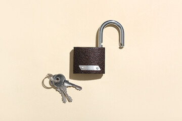 Open lock with keys on beige background. Crime concept