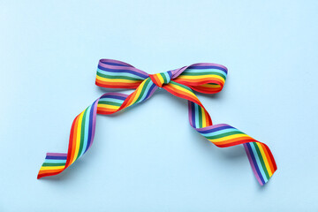 Fototapeta premium Bow made of rainbow ribbon on blue background. LGBT concept