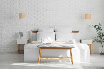 Interior of hotel room with bed, soft bench and lamps