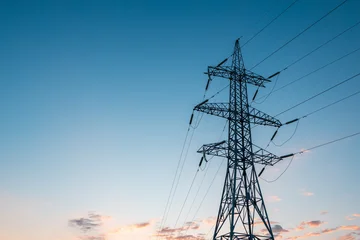 Selbstklebende Fototapeten Blue Jeans silhouette of a single pole of high-voltage electricity transmission lines against the blue sky at dawn  © metelevan