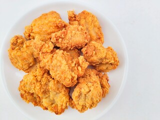 Breaded fried chicken in a white plate on a white background.