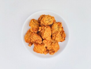 Breaded fried chicken in a white plate on a white background.