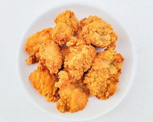 Breaded fried chicken in a white plate on a white background.