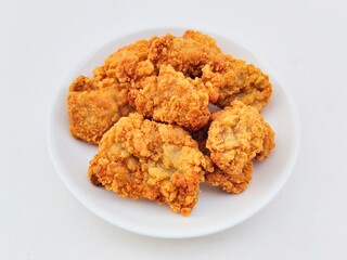 Breaded fried chicken in a white plate on a white background.