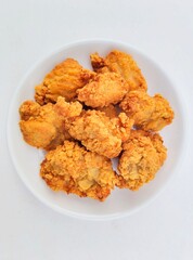 Breaded fried chicken in a white plate on a white background.