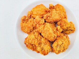 Breaded fried chicken in a white plate on a white background.