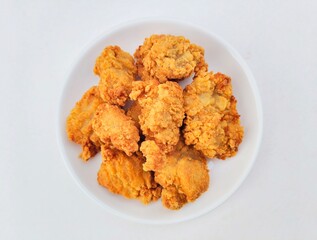 Breaded fried chicken in a white plate on a white background.