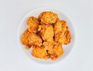 Breaded fried chicken in a white plate on a white background.