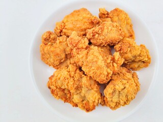Breaded fried chicken in a white plate on a white background.