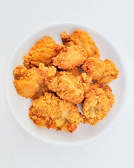 Breaded fried chicken in a white plate on a white background.