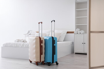 Interior of hotel room with bed, closet and suitcases