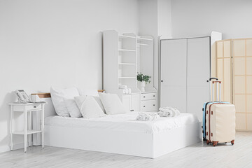 Interior of hotel room with bed, closet and suitcases