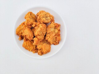 Breaded fried chicken in a white plate on a white background.