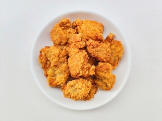 Breaded fried chicken in a white plate on a white background.
