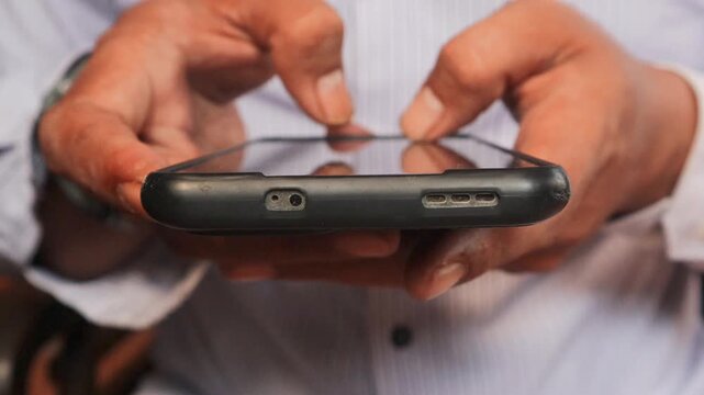 Close up view of man's hands typing a message on a smart phone. 