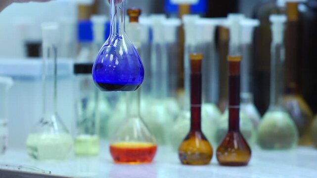 Химик наливает синюю жидкость в колбу в лаборатории