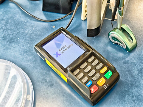 Kirov, Russia - July 21, 2025: Payment terminal displaying bank logo on a blue countertop with office supplies nearby