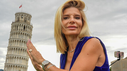 Female student proudly posing with laurel crown beneath Pisa’s iconic Leaning Tower after...