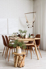 Interior of room with dining table, fir branches and paintings