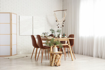 Interior of room with dining table, fir branches and paintings