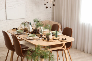Dining table set with pine cones and branches in room