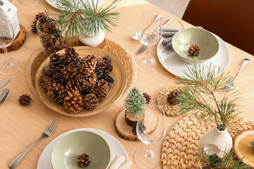 Winter table setting with pine cones and branches in room, top view