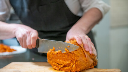 Close-up of hands cutting salami and prosciutto with a sharp knife for a charcuterie plate