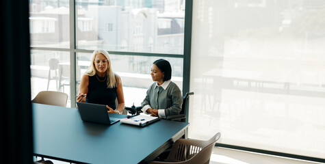 Two women discussing a project in a modern office setting