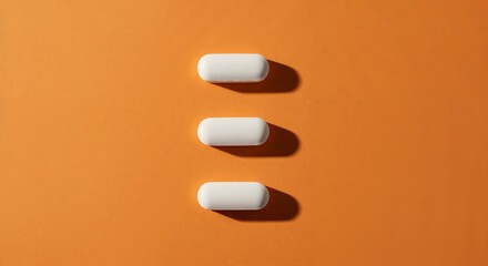 Three white oblong pills in a stark vertical line on orange for treatment