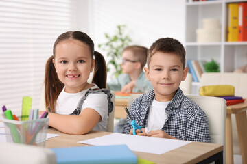 Portrait of cute children at wooden desk during art lesson in elementary school