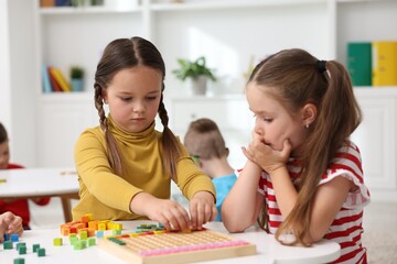 Fototapeta premium Cute children at white tables during lesson in elementary school