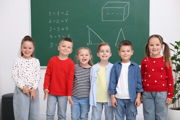 Group of happy pupils in front of chalkboard in elementary school