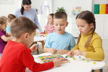 Obraz premium Cute children and teacher at white tables during lesson in elementary school
