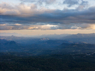 Vast mountain landscape under cloudy sky at dusk with layers of hills in the distance