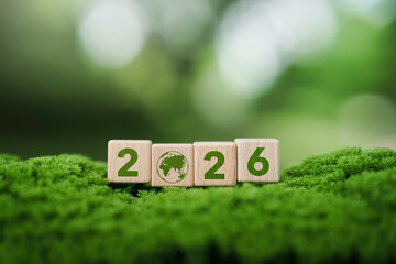 Wooden blocks with number 2026 and earth icon on green moss background for Sustainable...