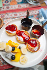 Syrniki with berry sauce banana mango and blueberries overhead