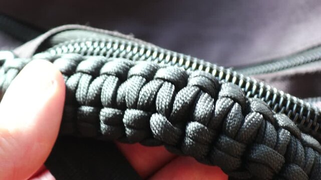 A person holding a black paracord for climbing or outdoor activities
