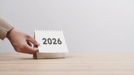 Business woman hand change 2026 Year Calendar on table in office background. countdown to Happy New...
