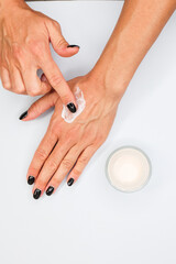 Mano mentre stende della crema per le mani sul dorso di un altra mano su uno sfondo neutro 