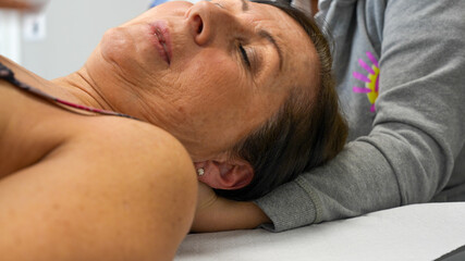 Physiotherapist performs neck massage on a woman for pain relief and relaxation
