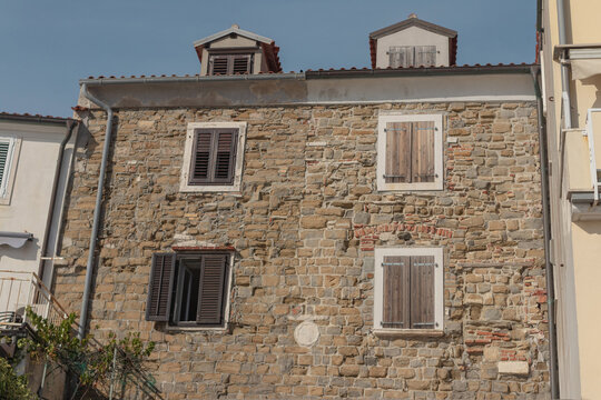 "Historic stone facade with wooden shutters and tiled roof in Adriatic town